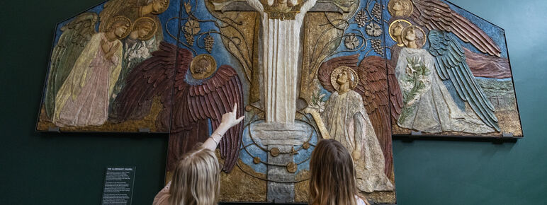 Two visitors point at decorative panel