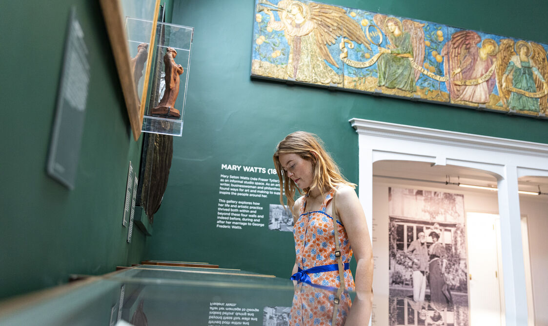 Visitor looks at glass display case in green-walled gallery