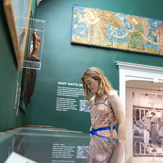 Visitor looks at glass display case in green-walled gallery