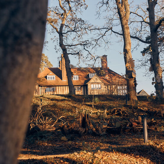 An outdoor shot of Limnerslease, a large building with many windows surrounded by woodland