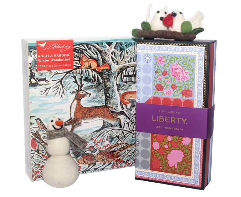 Product photograph of shop items. On the left is a puzzle box, with a winter image of a deer in the snow on the front of it, and on the right is a decorative two in one games box with a floral design on. Placed in front of the puzzle is a felted tree decoration of a snowman, and placed on top of the two in one games box is a felted tree decoration of two doves on a stick.