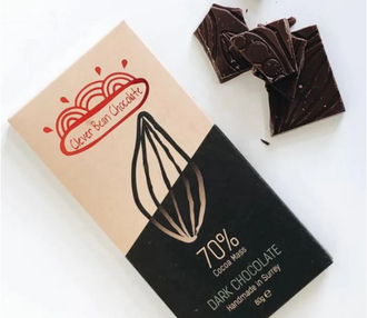 A bar of Clever Bean Chocolate in it packaging with some loose squares on a white background