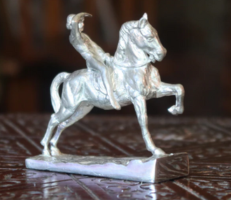 A silver paperweight in the form of George Watts's famous Physical Energy sculpture