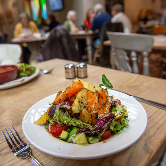 A large salad topped with roasted vegetables on a white plate