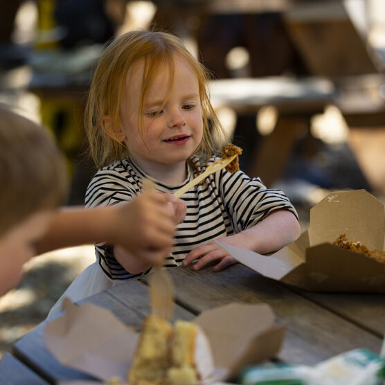 Two children eating cake on a picnic table