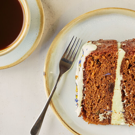A slice of cake with white filling between layers and a cup of black coffee