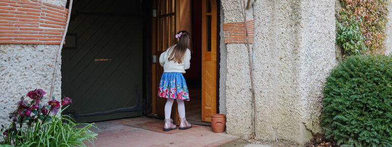 A little girl opens the door to Watts Gallery building