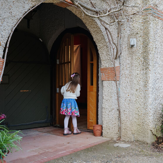 A little girl opens the door to Watts Gallery building