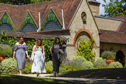 Three visitors walking outside gallery surrounded by gardens