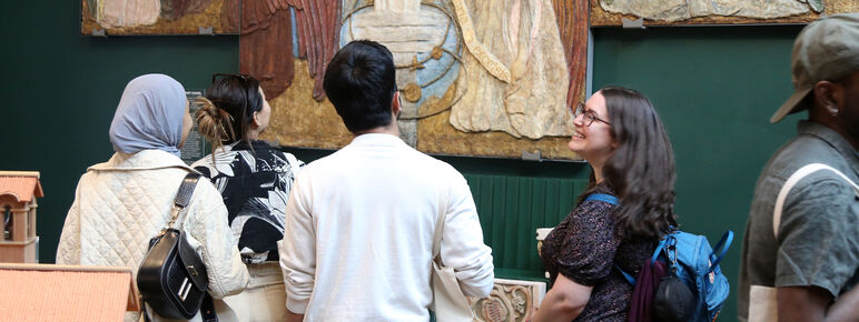 A group of college students look at a large altarpiece in the Mary Watts gallery