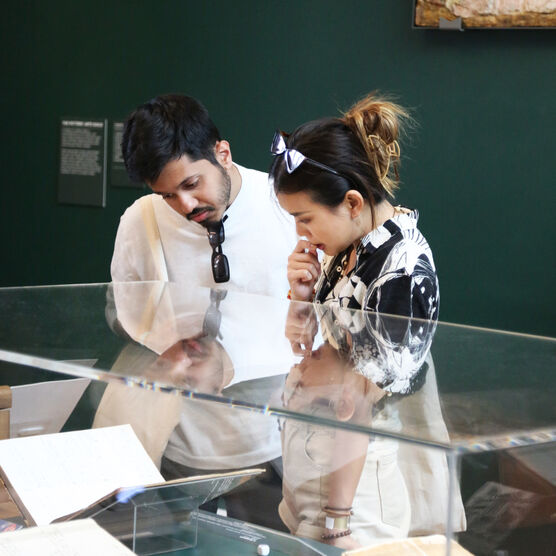 Two college students look down at a glass display case in the Mary Watts Gallery