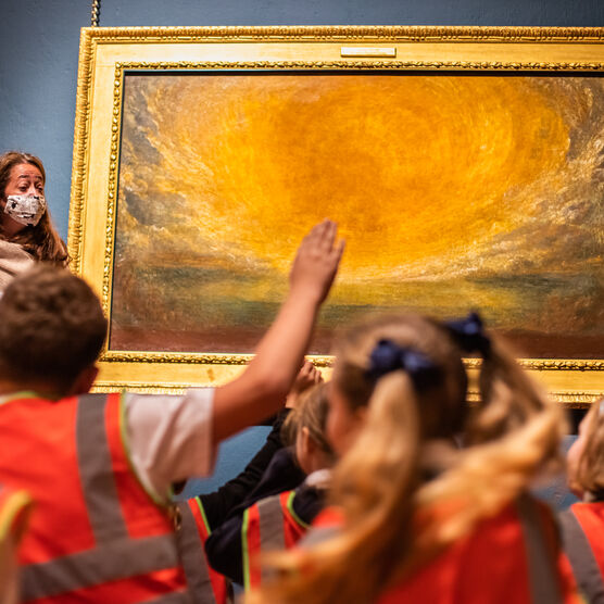 School children sit in front of the gold-framed oil painting of the sun
