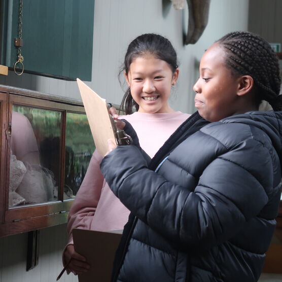 Two students hold a clipboard up in the gallery