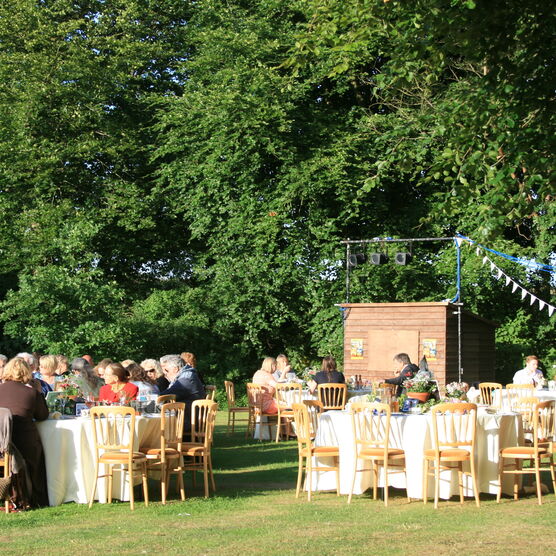 Guests sit at tables outside, laid with white table cloths
